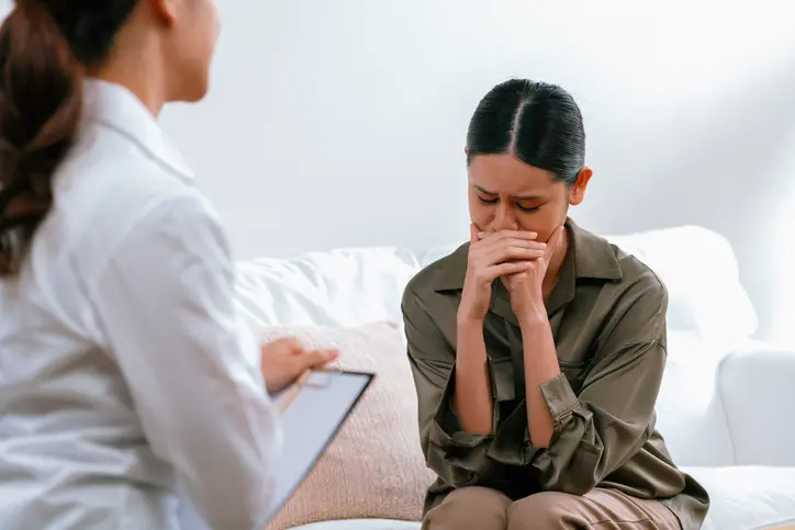 Woman in therapy session, visibly distressed.