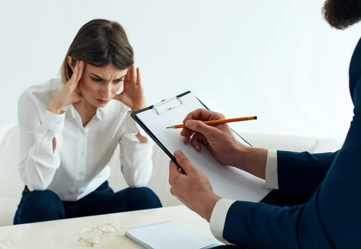Woman stressed during counseling session with clipboard.